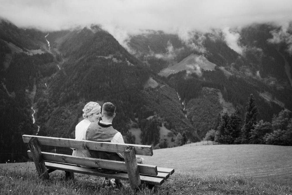 17 Hochzeitspaar sitzt auf einer Bank mit Blick auf die Berge.jpg