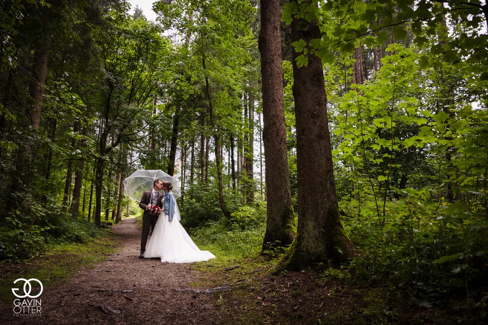 Brautpaar küsst sich im verregneten Wald.jpg