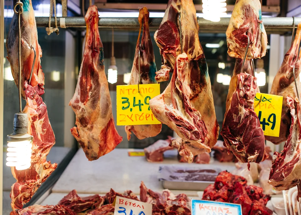 Large cuts of meat are hung out on display for purchase.