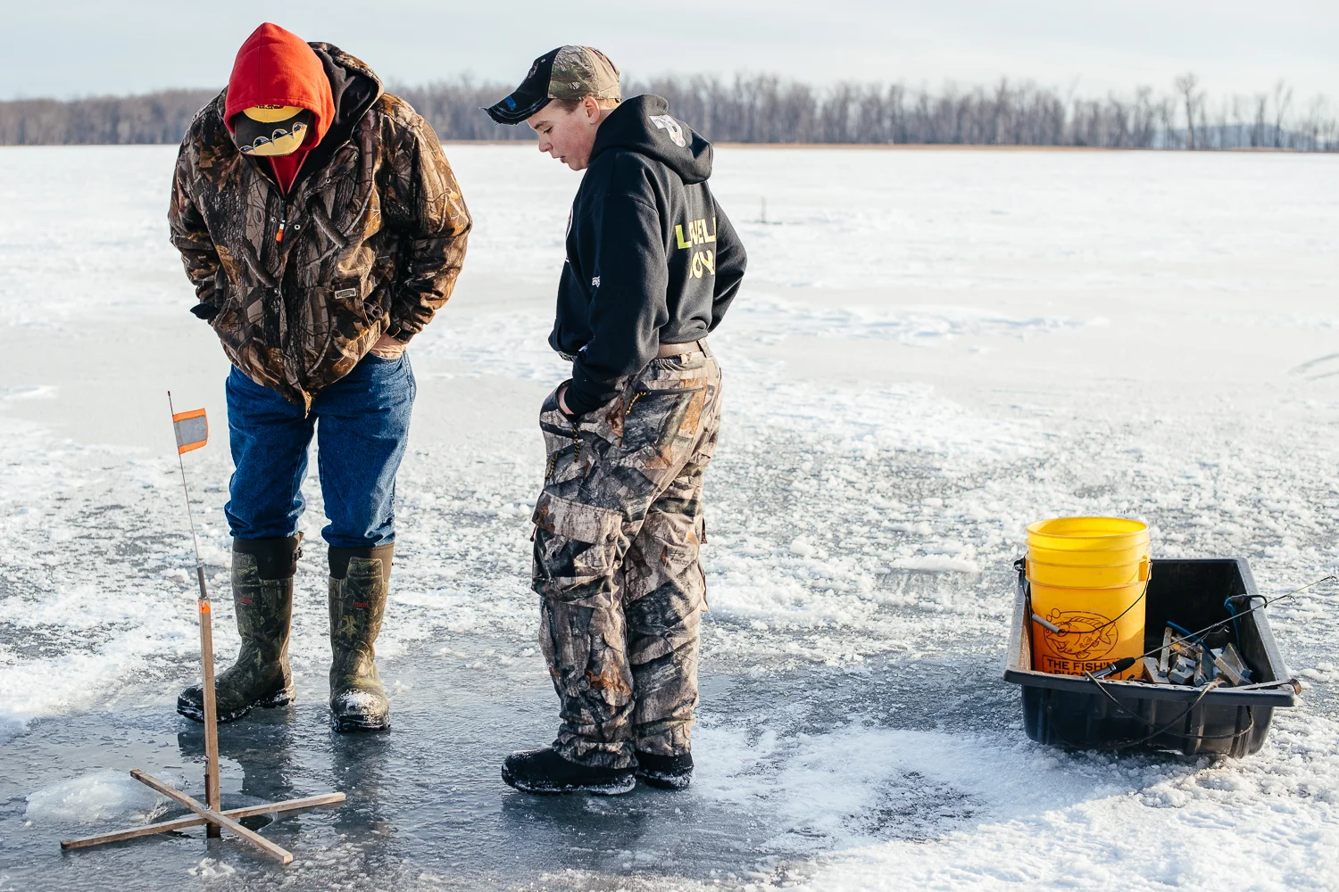 Father and son checking the line as the tip up indicates they have a fish on the line. 