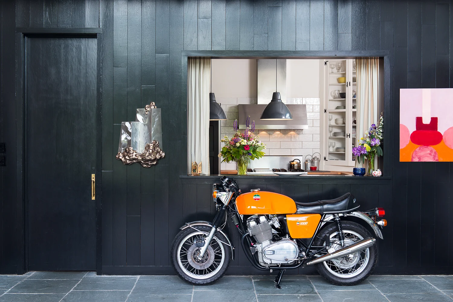 Entryway looking into the kitchen with a classic Laverda 1000 motorcycle.