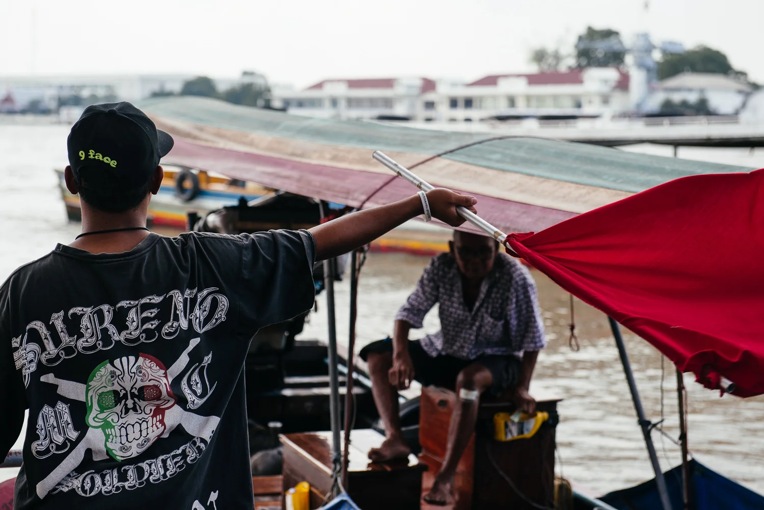 Worker waves in a long-tail boat.
