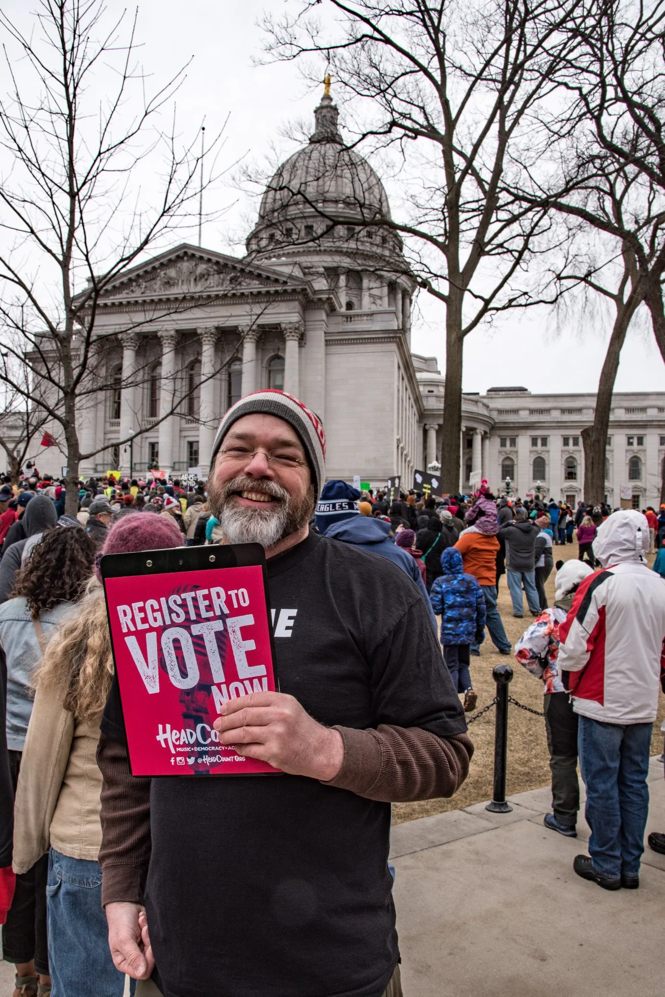 Voter Service Chair Paul Lindquist in his Dane County Voter ID Coalition "ASK ME . . . ABOUT VOTER ID" shirt, worked with HeadCount to help voters begin the registration process.