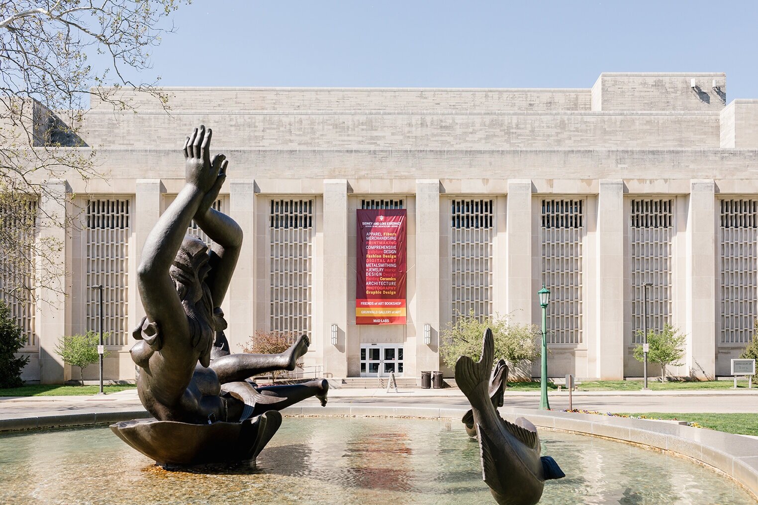  Image of one of the Eskenazi School buildings behind the Showalter Fountain, highlighting a designed banner featuring all fourteen areas of study in the school 