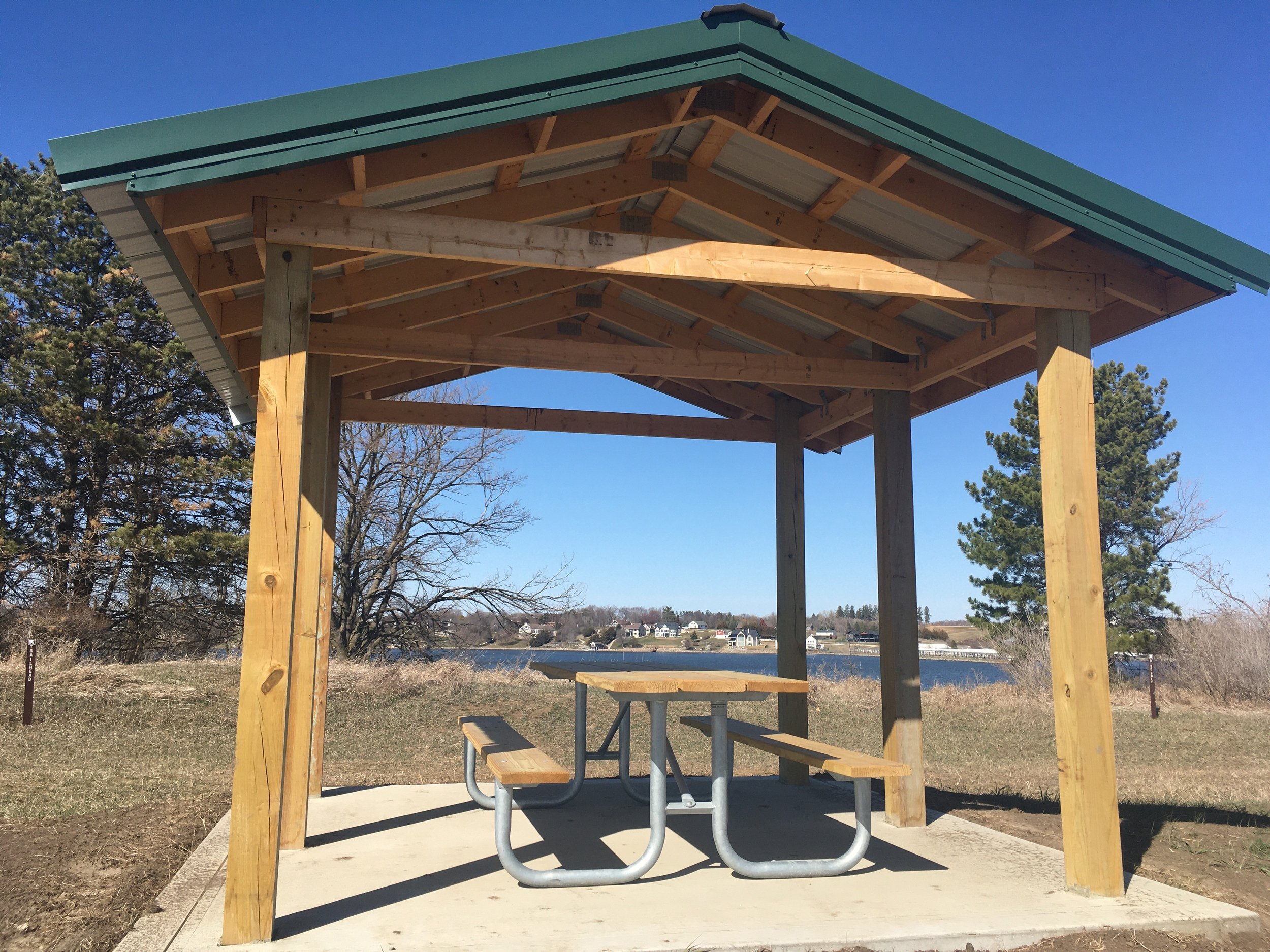 This shelter was built last fall near the south shore recreation parking lot, with the picnic table added early this spring. Brown sign posts near the shelter point the way to the beginnings of the disc golf course to the right, and the trail system