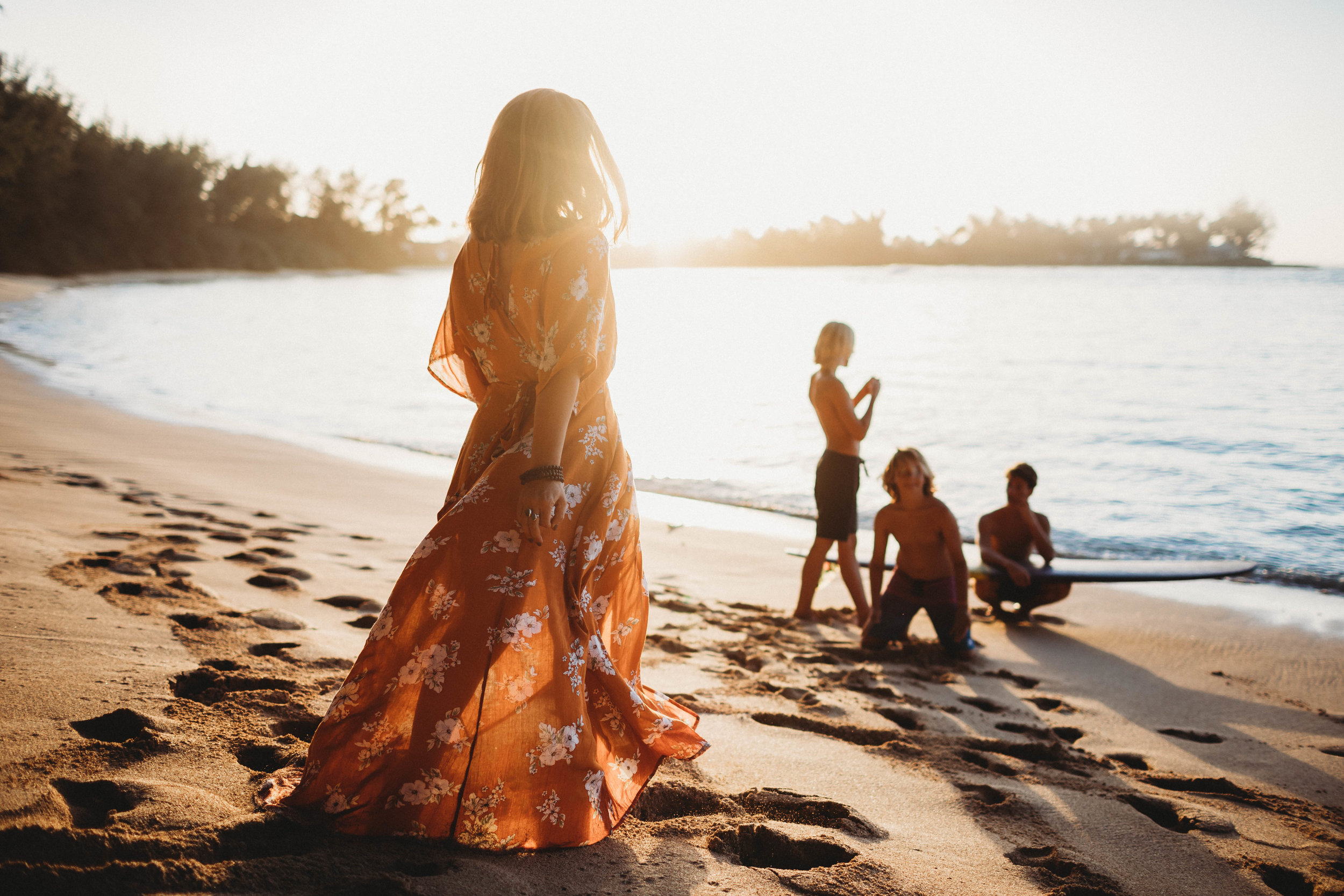  mother walking towards the sunlit beach with her three sons in the background  