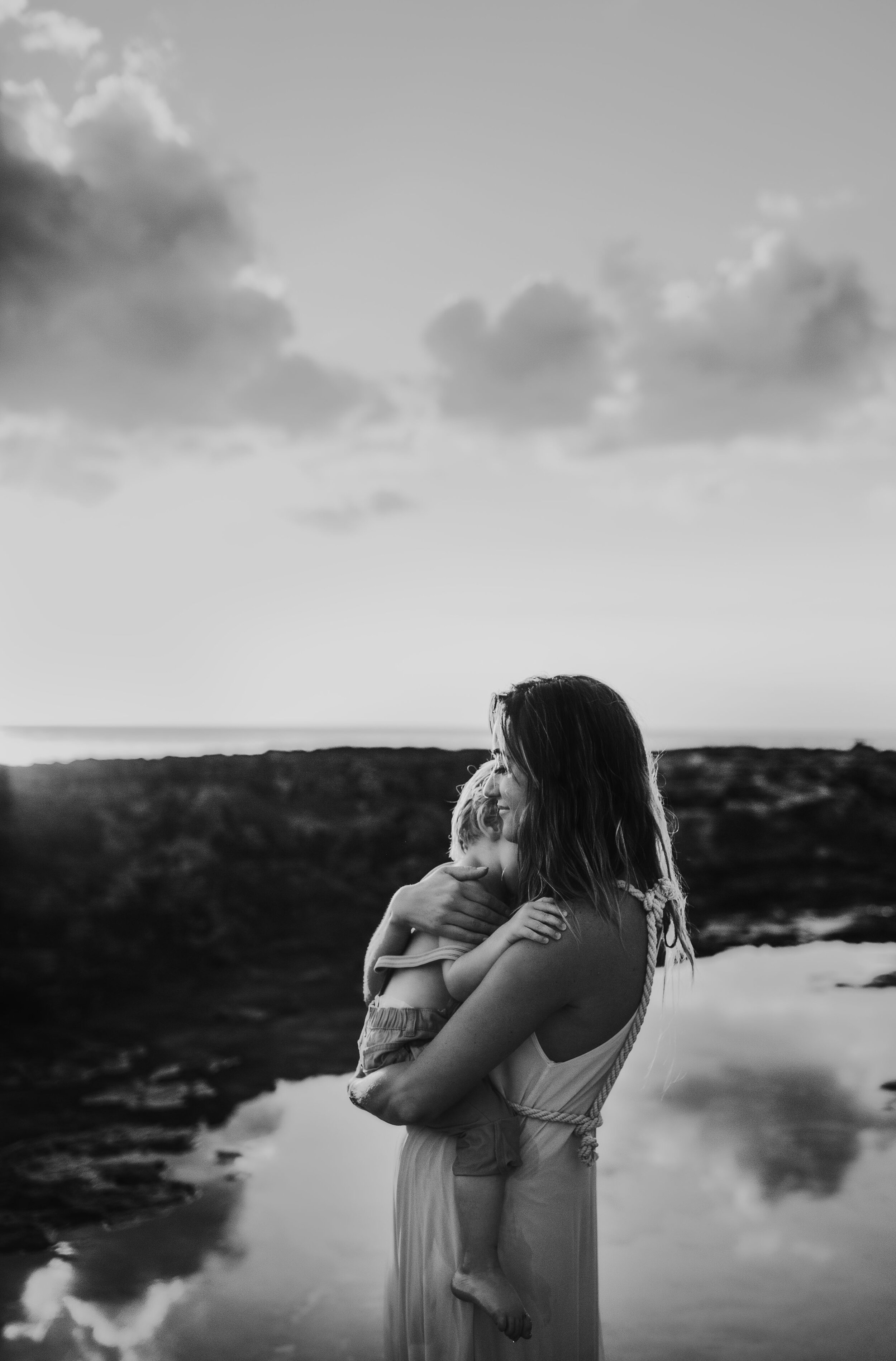  mother hugging her son on a beach 