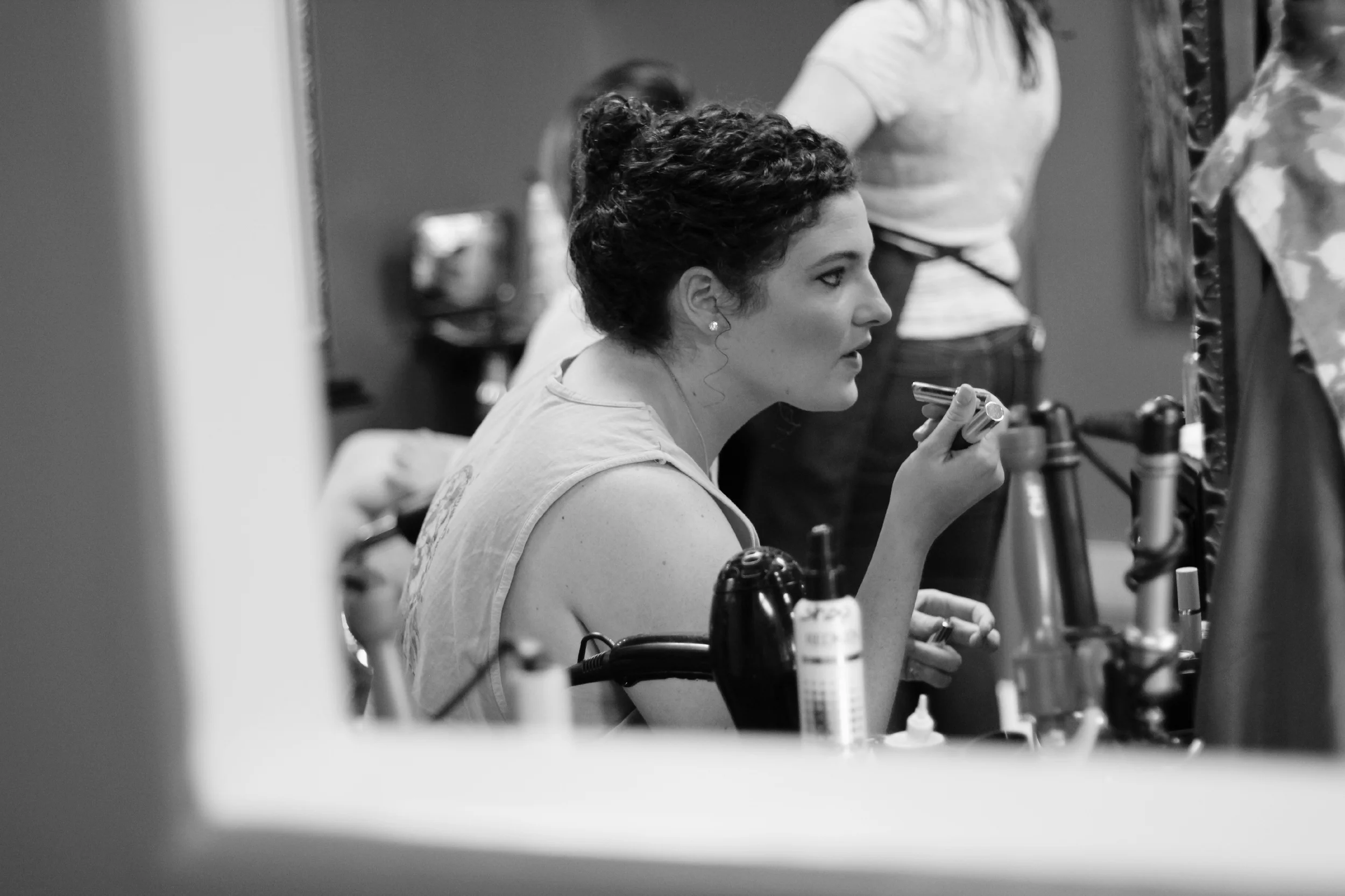 Wedding preparation photograph of bridesmaid putting on lipstick at Shear Attitude Salon in Ocean Springs, Mississippi