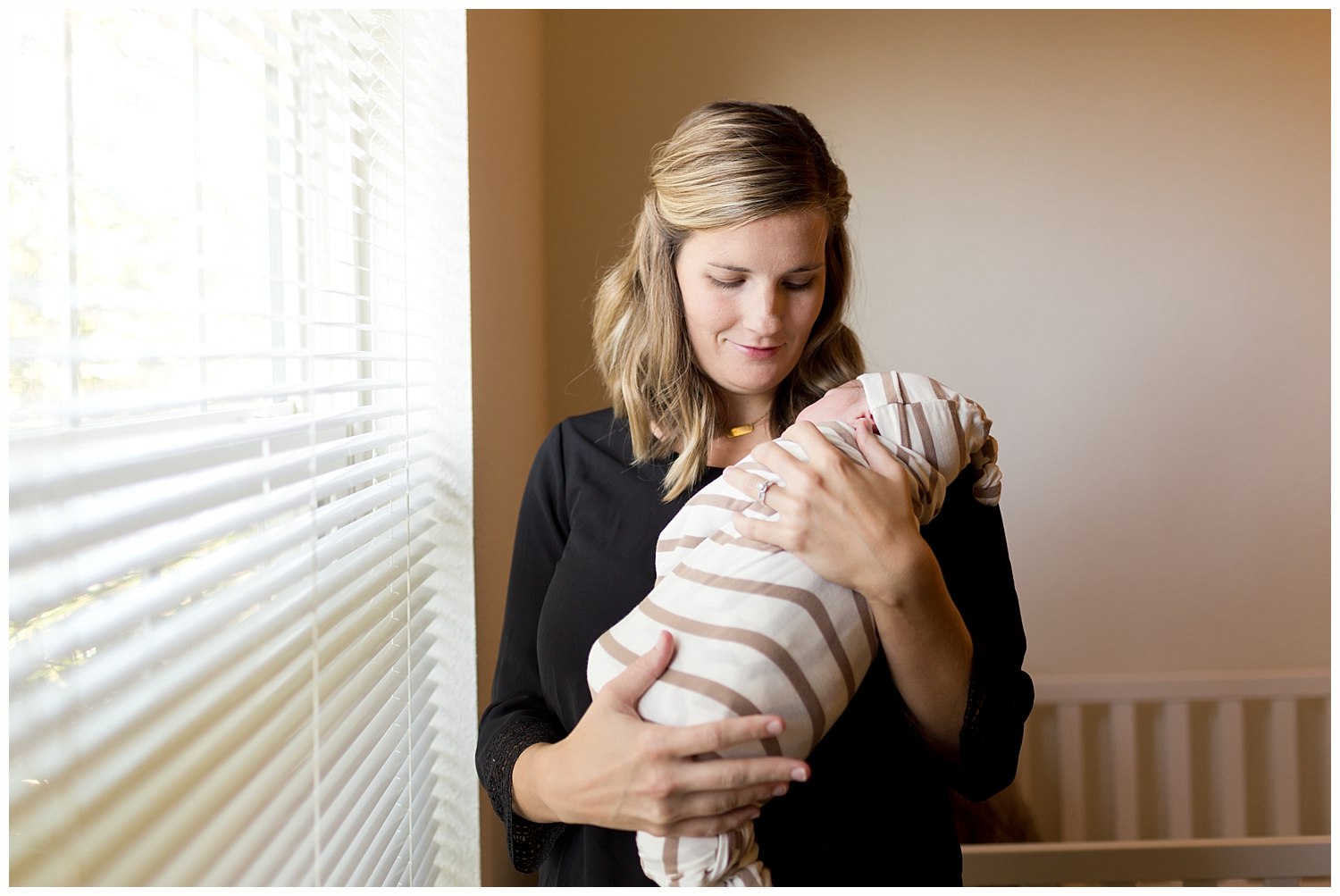 new mom with newborn baby boy with natural window light in nursery
