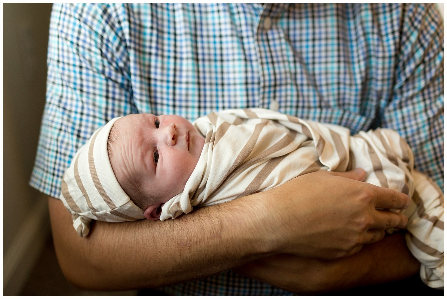 dad holding newborn baby boy in nursery