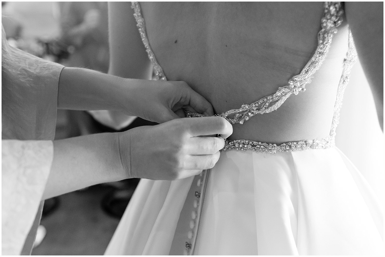 maid of honor helping bride put on gown