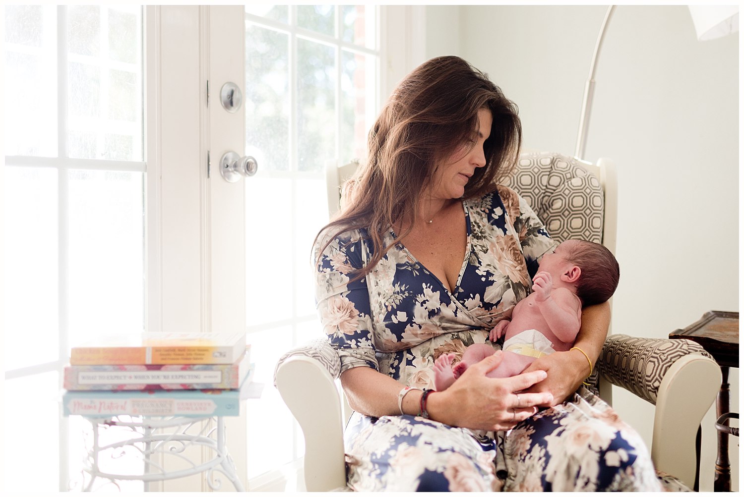 mother and newborn in nursing chair with books - Ocean Springs, MS