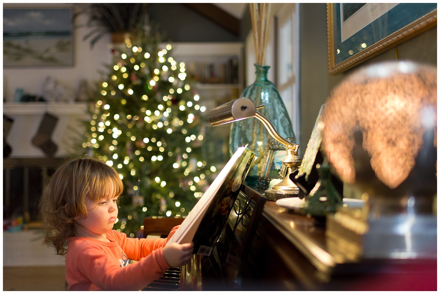 toddler girl playing piano with Christmas tree in the background