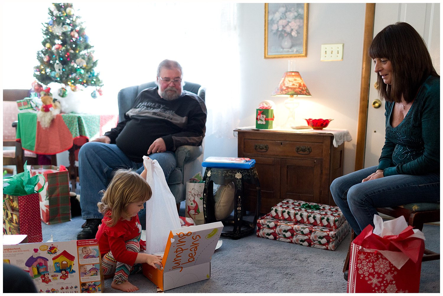 little girl opening Christmas present with great aunt and uncle