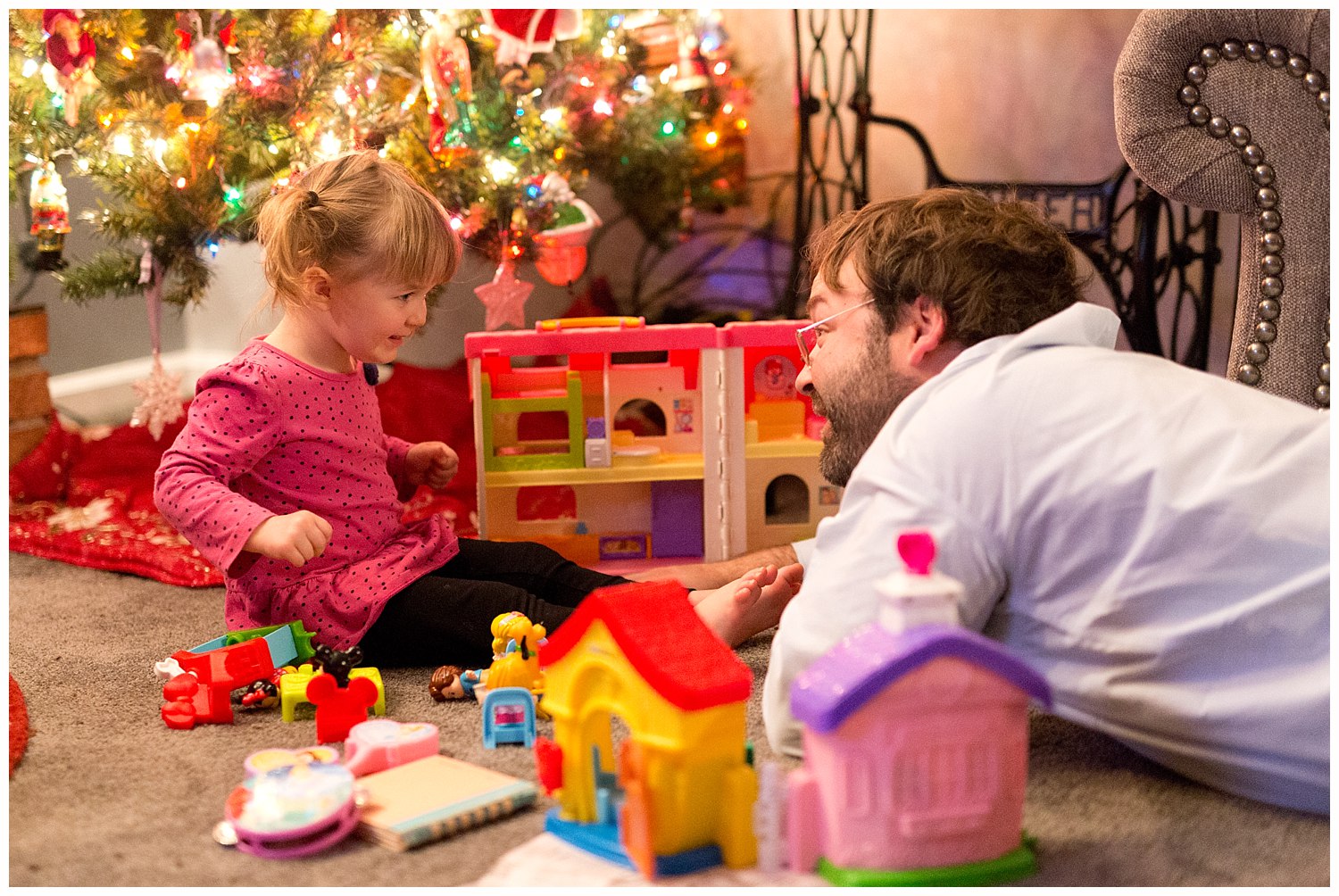 daddy and daughter playing under Christmas tree