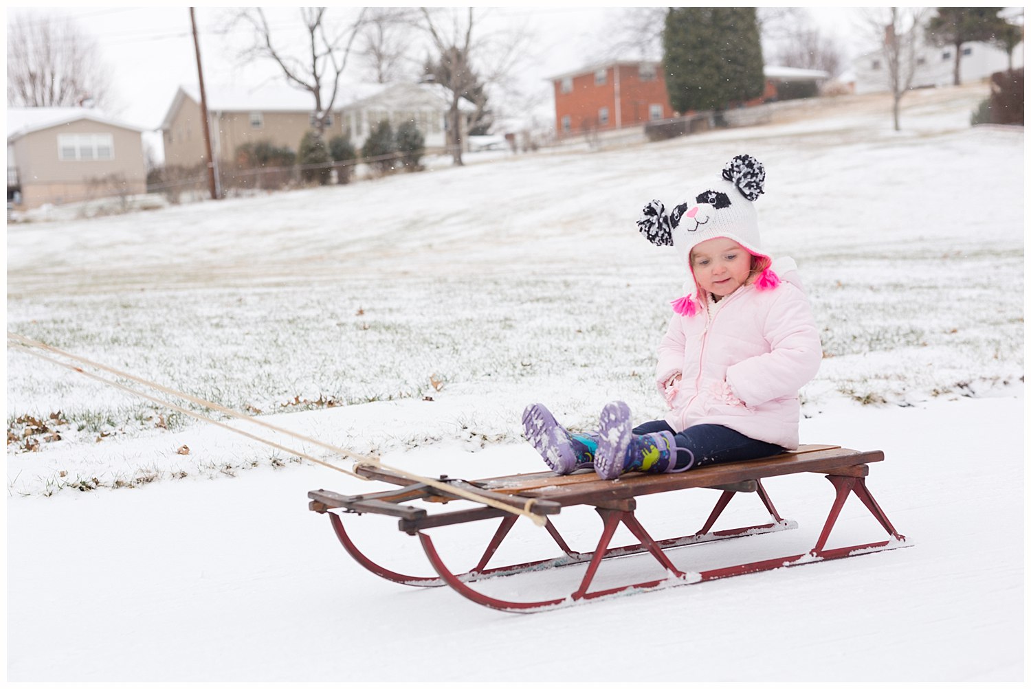 two-year-old girl on antique sled in the snow