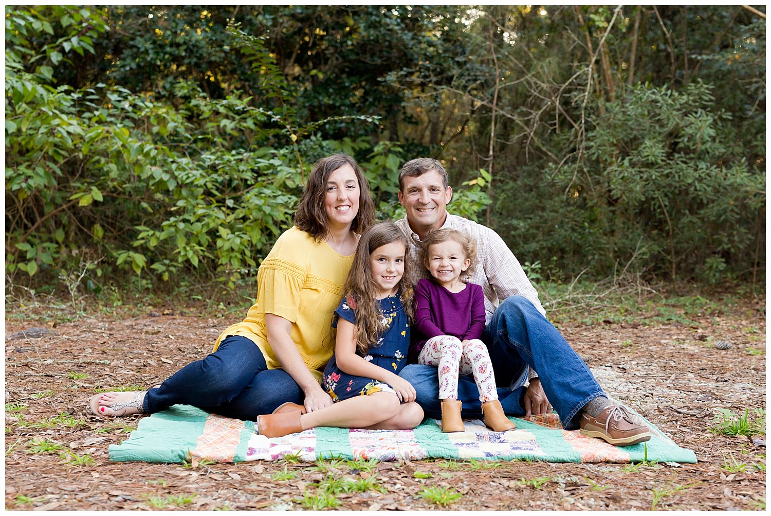 family portraits in Ocean Springs, Mississippi - family of four seated on a vintage quilt in the woods