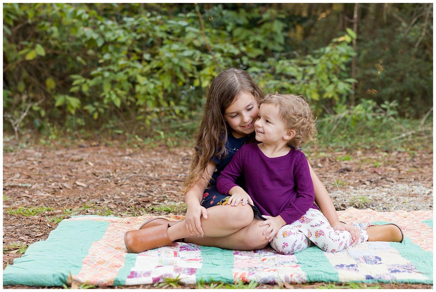 photo of two sisters on quilt in the woods