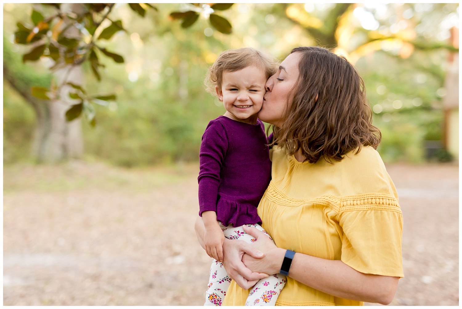 mom kissing 2-year-old daughter on the cheek