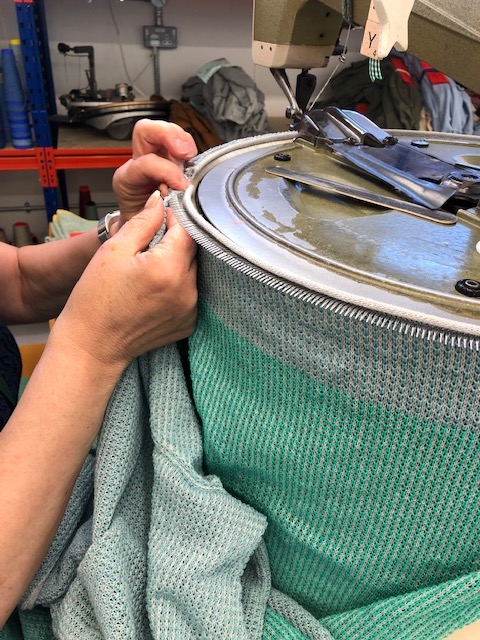 Skilled hands at work, exactly matching stitches o join the sweater panels together.
