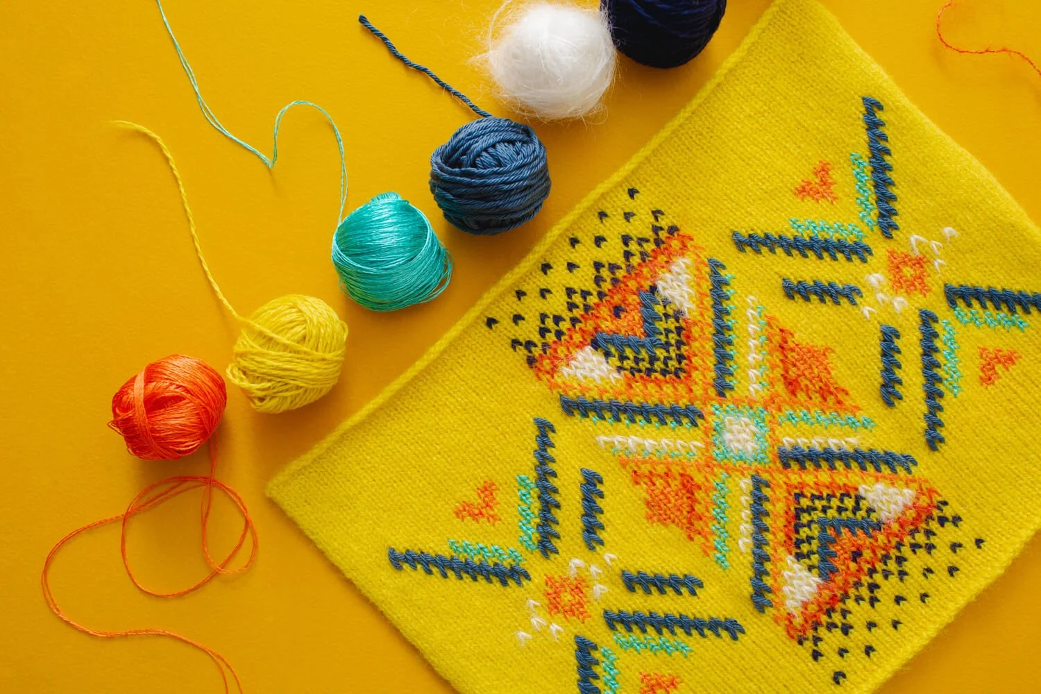 Bright yellow fabric with examples of swiss darning in multicolour yarns by Collingwood-Norris