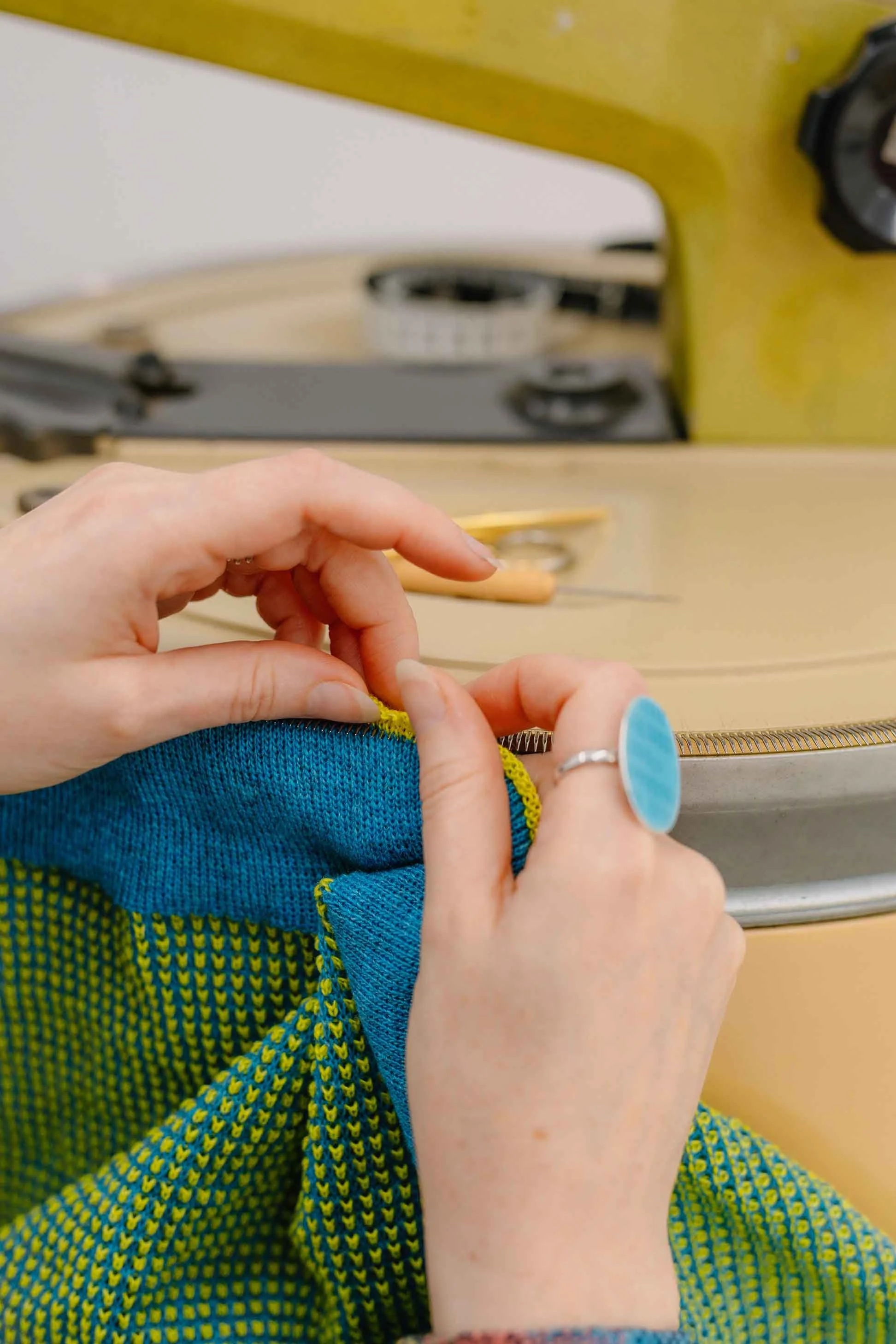 Close-up of hands linking a blue and yellow textured lambswool scarf by Collingwood Norris