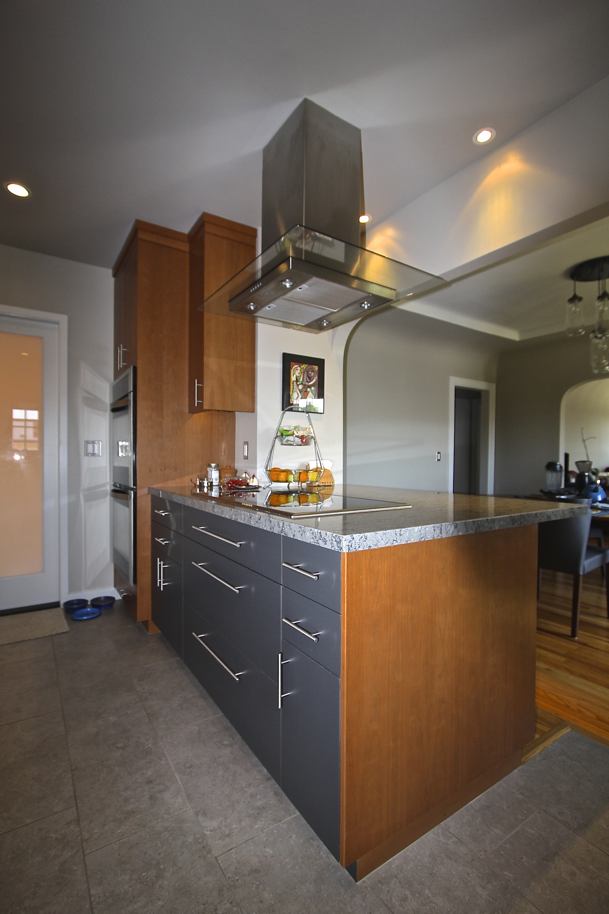 A nice mix of wood veneer and laminate cabinets create interest and balance the warm wood colors with cooler grays and blues of the tile, walls and countertop.