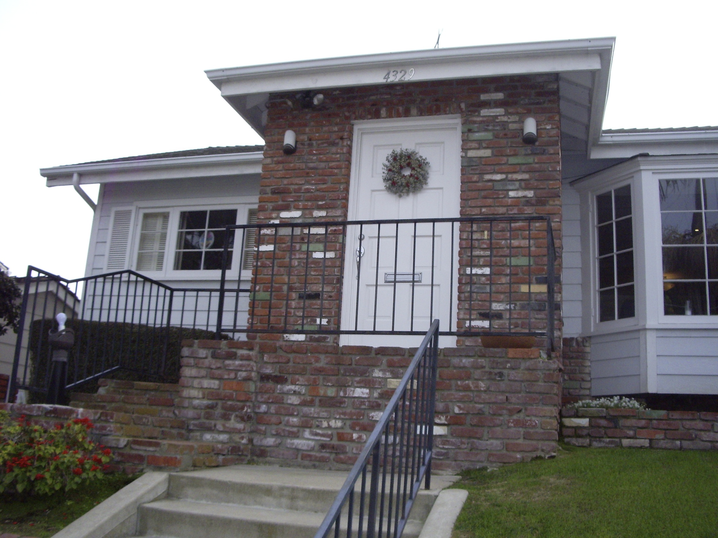 Before: Dangerous steps, dated looking brick facade and iron railings and useless sloped lawn.