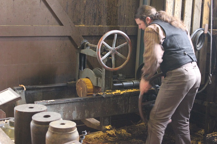A man building the spokes for a wheel at a 'wheelery'.