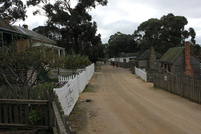 A residential street shared by both people and horses. Notice how there is no sidewalk - just one flat surface for everyone to share. There is a ditch for waste water on the left. A precursor to the curb?