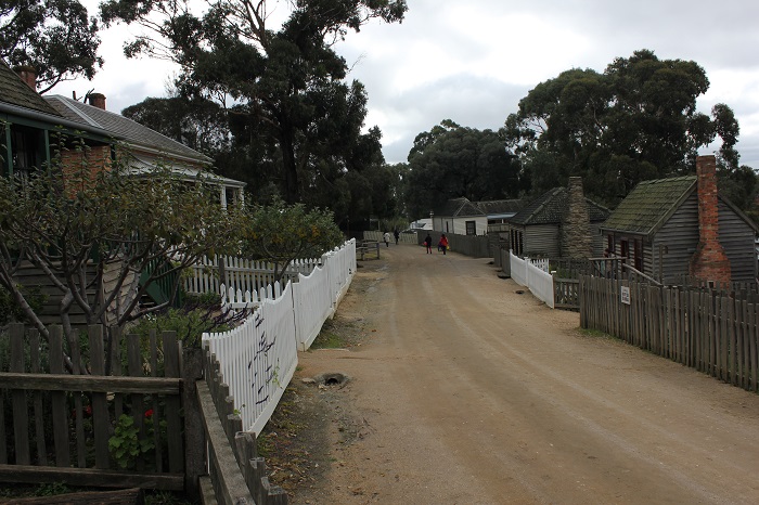 A residential street shared by both people and horses. Notice how there is no sidewalk - just one flat surface for everyone to share. There is a ditch for waste water on the left. A precursor to the curb?