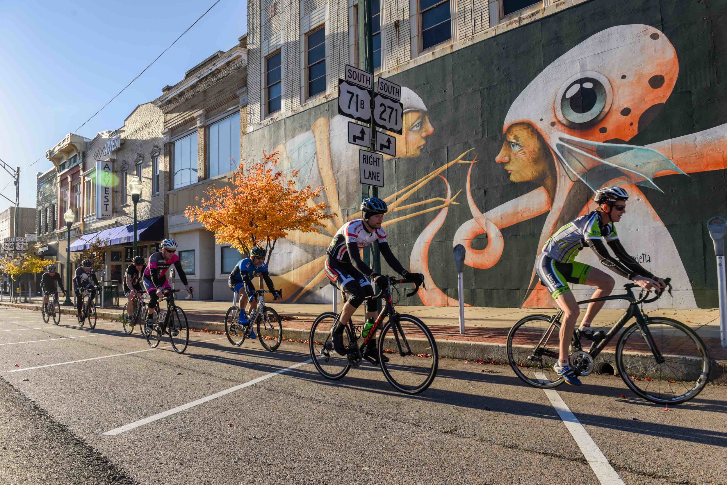  Cyclists in front of a mural painted as part of The Unexpected. (Source: 64.6 Downtown) 