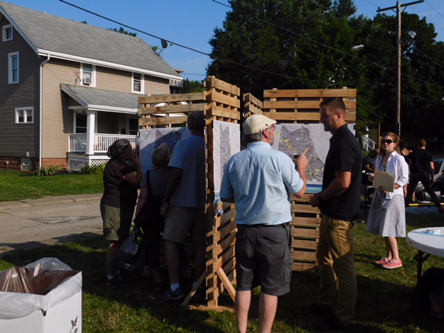 Zac Kohl stands near a display set up to solicit feedback on Akron's downtown vision and development plan from residents attending the Hapi Fresh Farmer's Market. (Photo: Tessa Skovira)