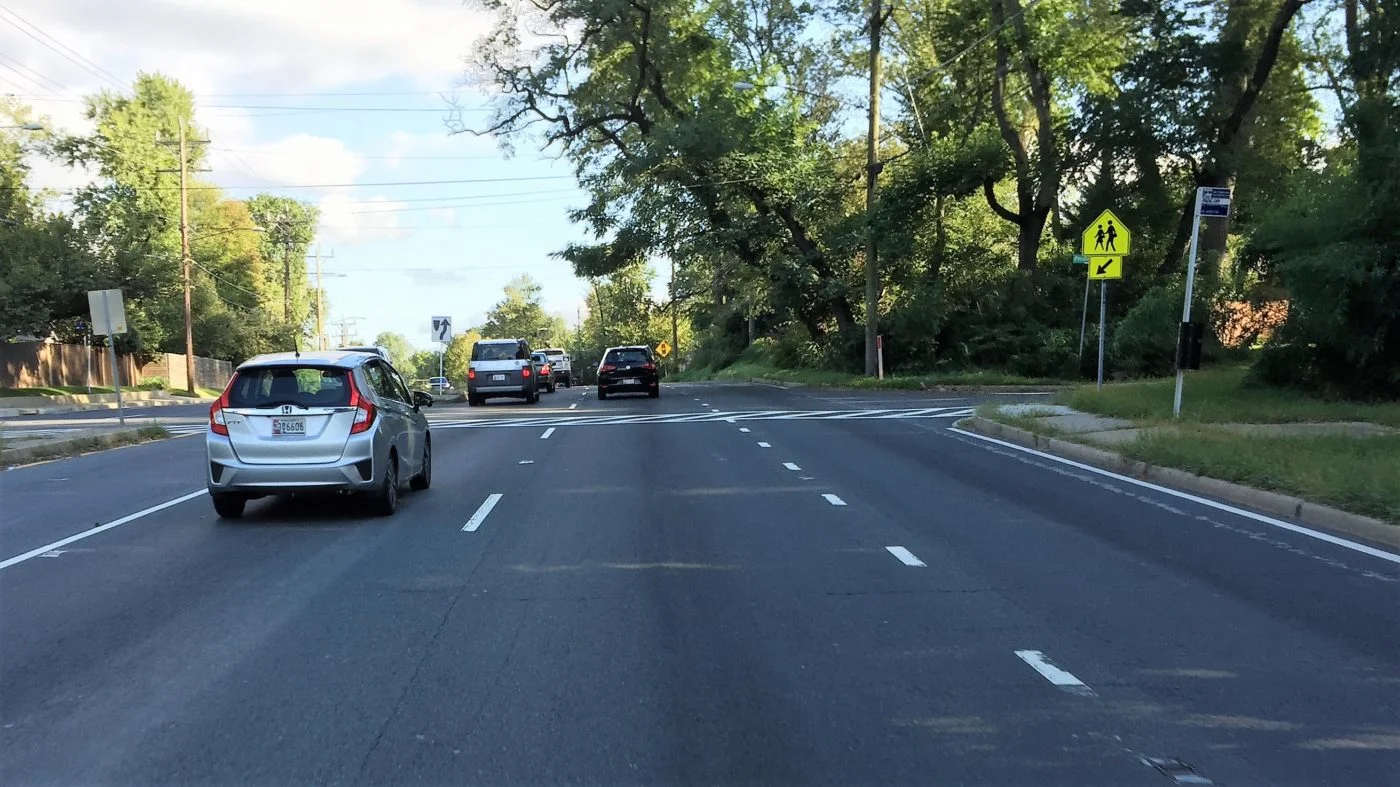This intersection is a school crossing and has a bus stop. There are no sidewalks approaching the intersection, or a traffic signal to allow a safe crossing. The road carries 40,000 vehicles per day moving at 40-50 miles per hour.