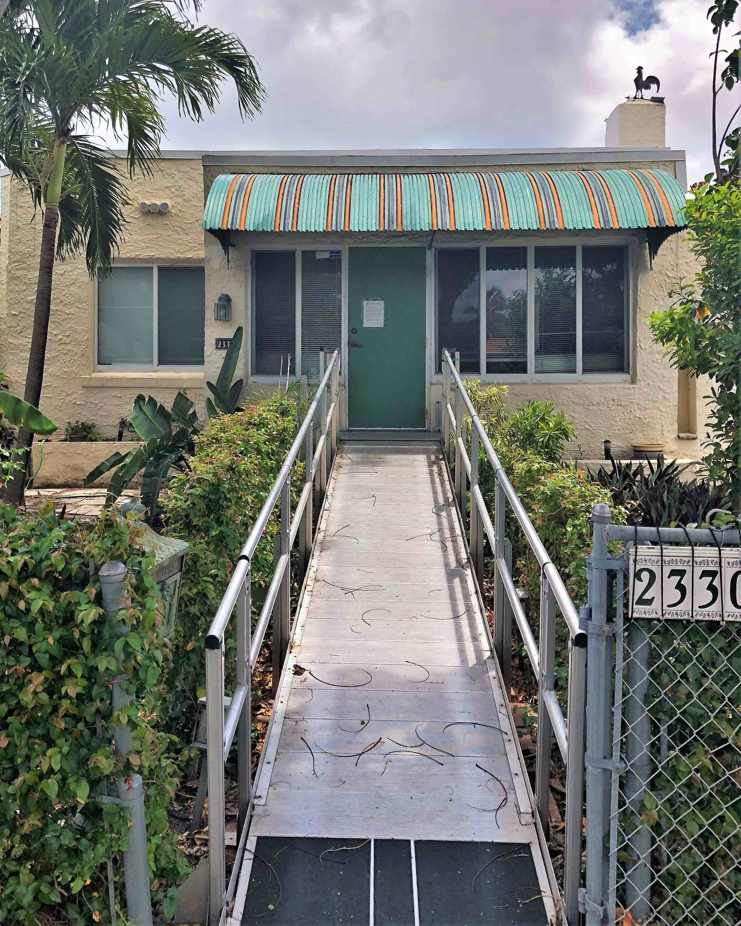 A ramp with non skid tape runs front door to sidewalk and serves a house elevated far above the flood plain in Miami, ground zero for sea-level rise.