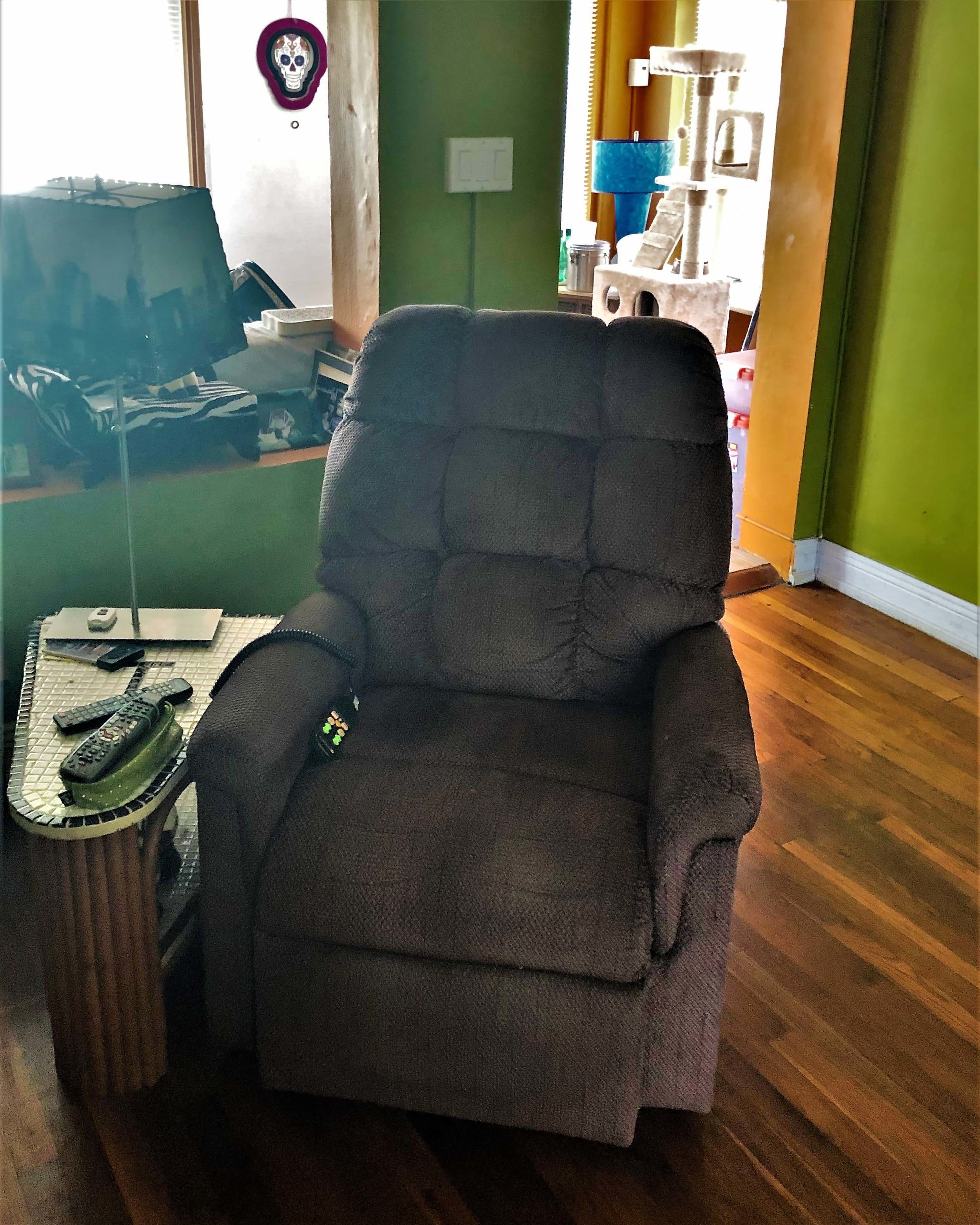 Stylish lift-zero gravity chair. A reclaimed table from an art deco hotel holds remotes for fans, lights, and electronics. Tropical colors accent the restored hardwood floor.