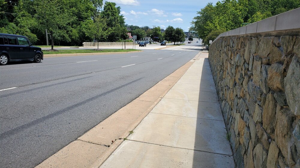 There is nothing except the highway gutter separating pedestrians from traffic on this segment of the sidewalk.