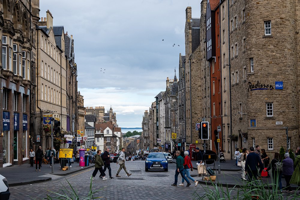 People walk past historic buildings in Edinburgh.