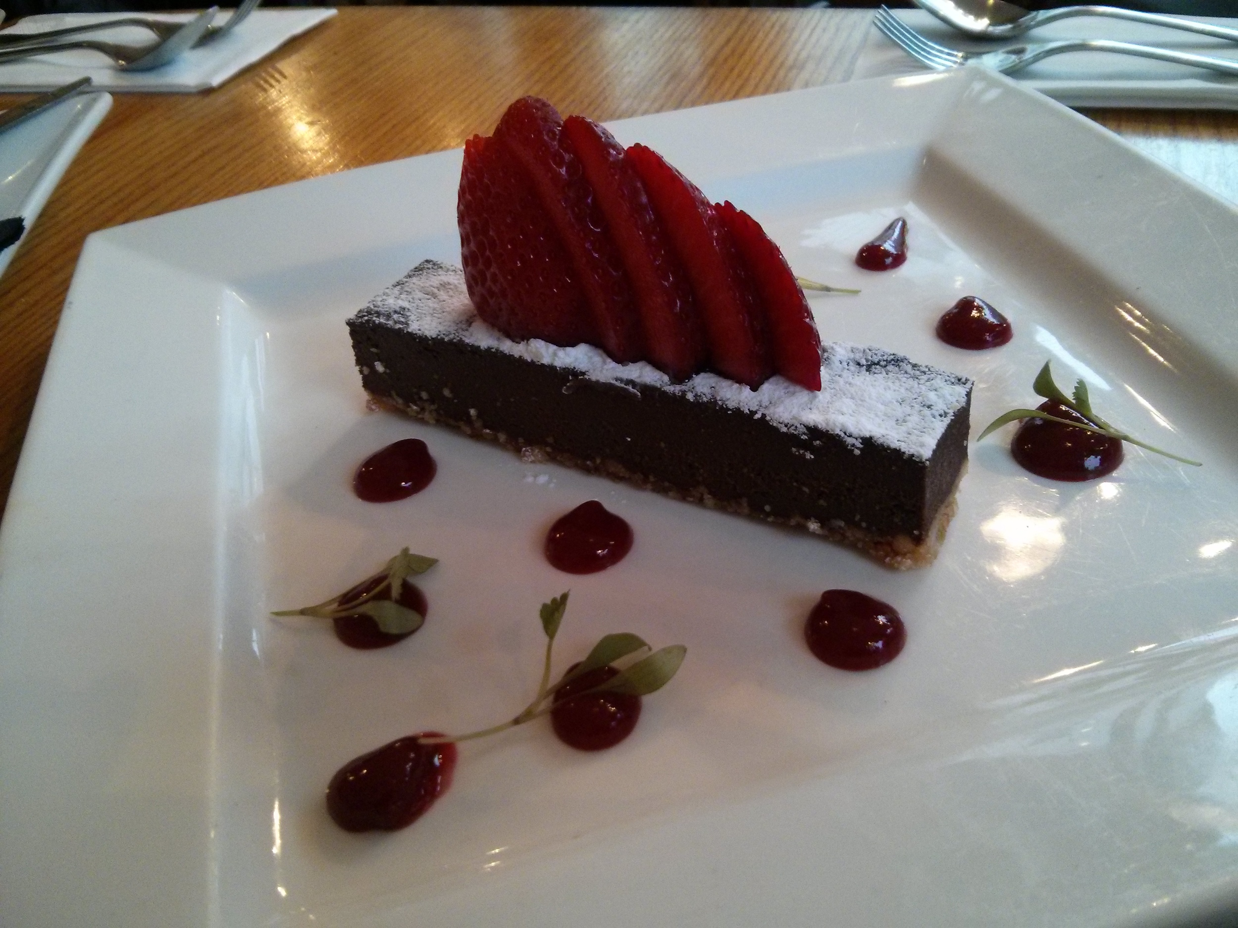 Chocolate truffle torte baked on a hazelnut biscuit base served with berry coulis