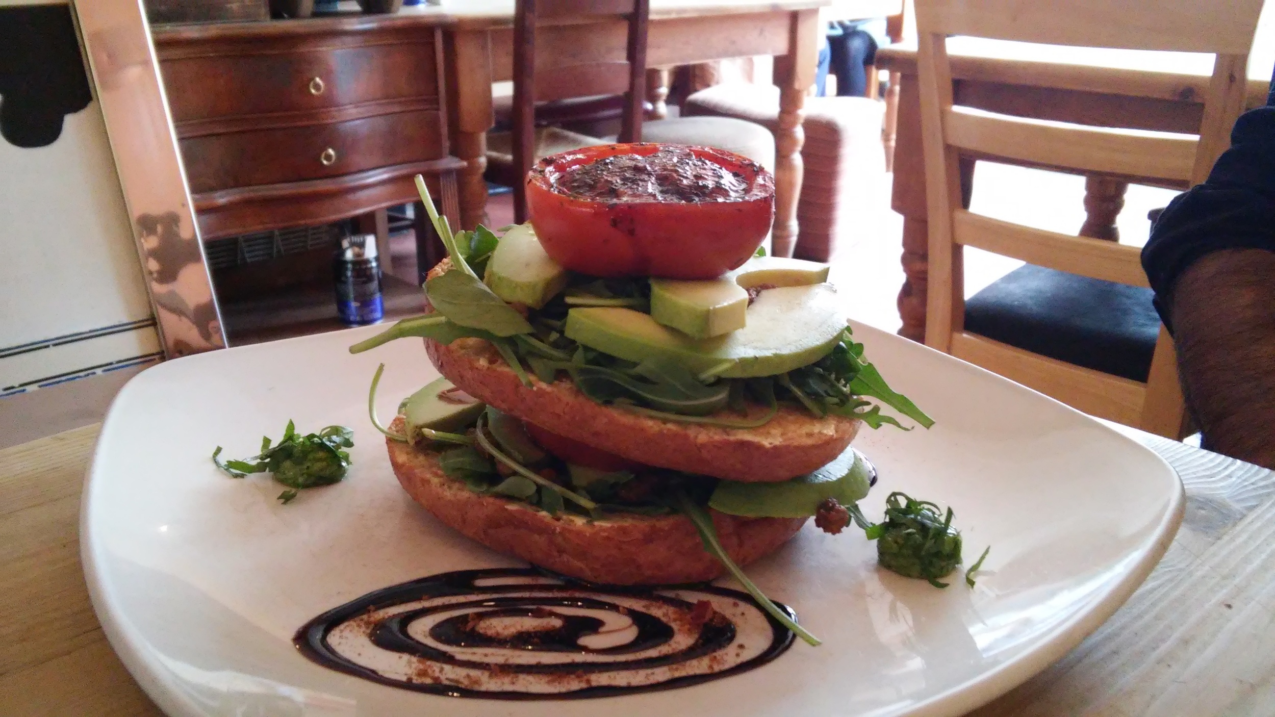 The griddle bagel with avocado, slow roast balsamic tomato, fresh rocket and cashew nut pesto topped with a balsamic reduction