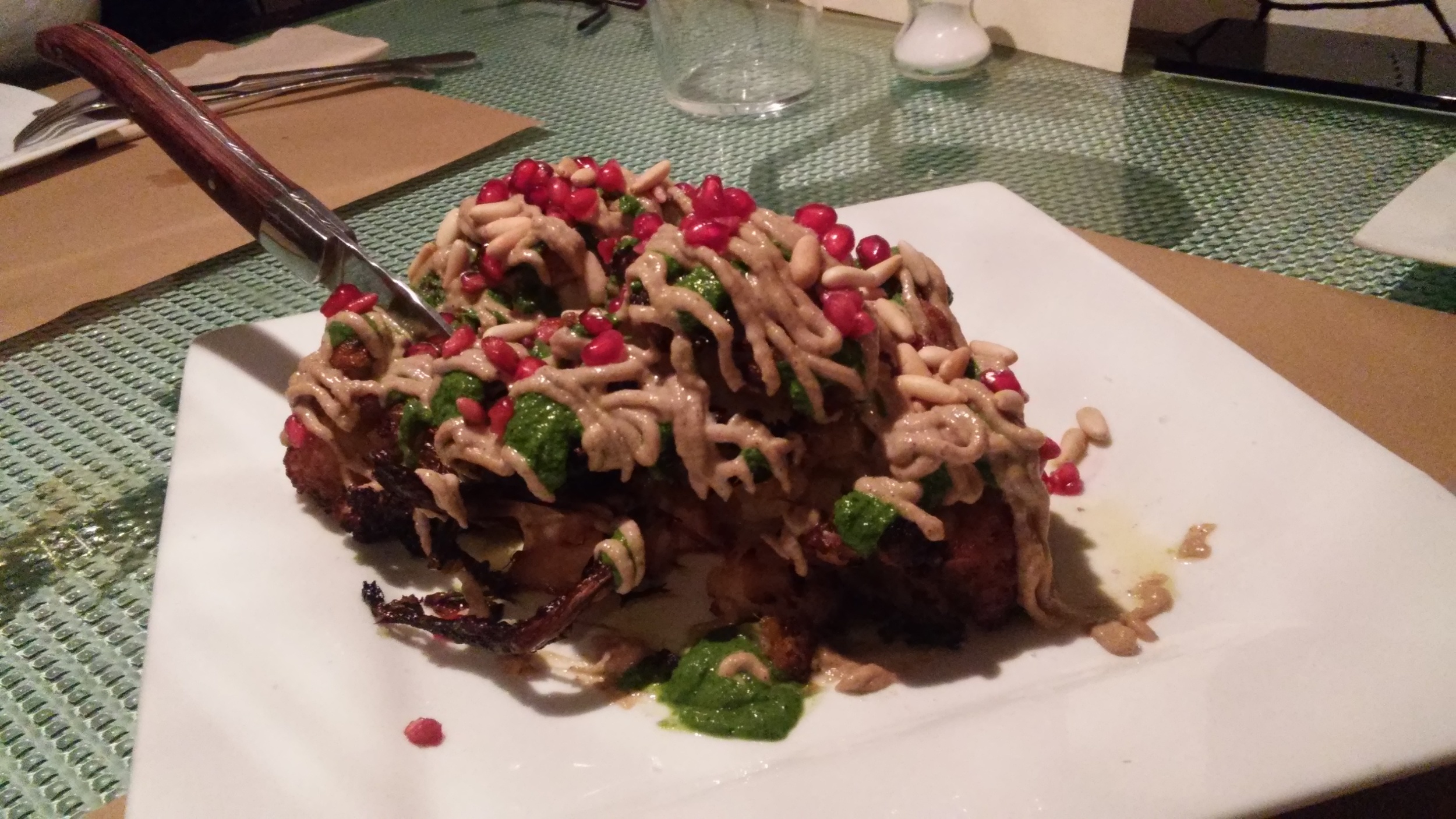 Baked cauliflower with tahini sauce, coriander, green chilli sauce, pine nuts and pomegranate