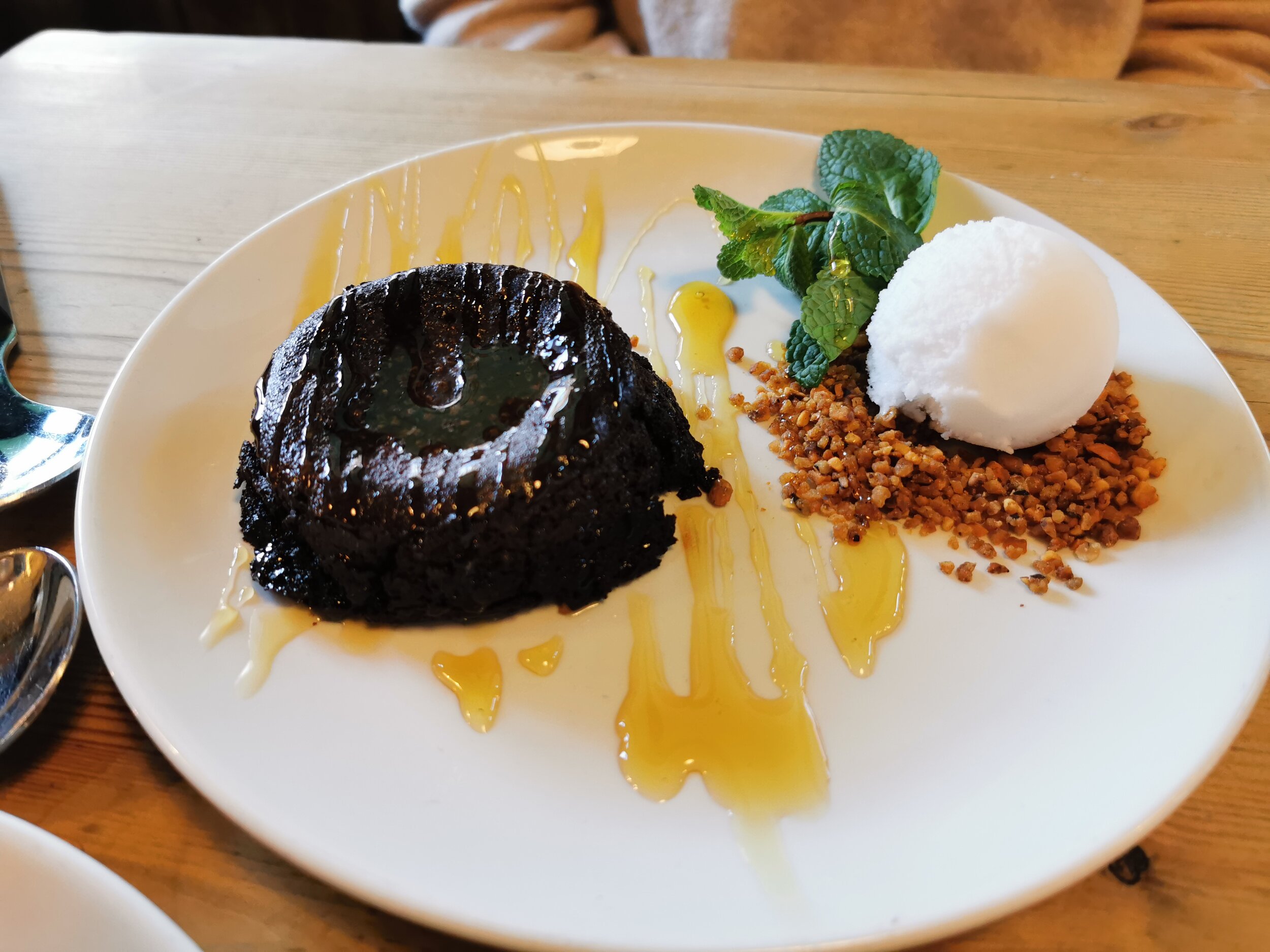 Sticky Chocolate Pudding drizzled with syrup, icing sugar &amp; hazelnut crumb, served with a scoop of coconut ice cream