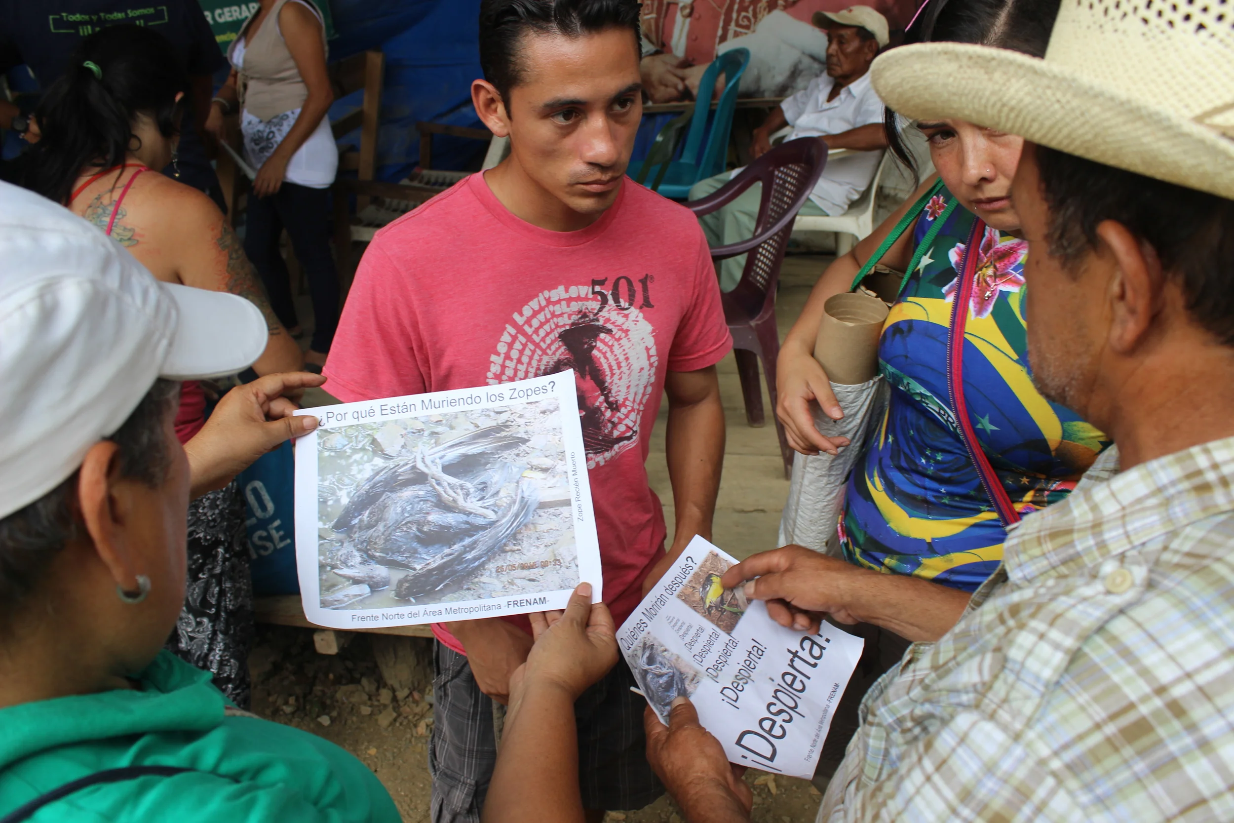 Miembros de la resistencia muestran a visitantes evidencia fotográfica del impacto de la contaminación minera en la vida silvestre. Resistance member showing visitors photographic evidence of the destruction of wildlife resulting from pollution from the mine.