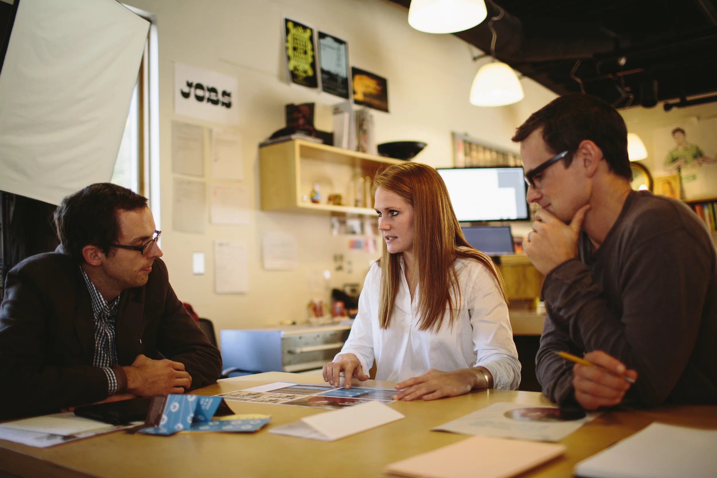 BROOKE DISCUSSES A PROMOTIONAL CHRISTMAS PIECE FOR FORGOTTEN VOICES WITH PRESIDENT RYAN KEITH (LEFT) AND RETURN DESIGN DIRECTOR, TIM FERGUSON SAUDER (RIGHT).