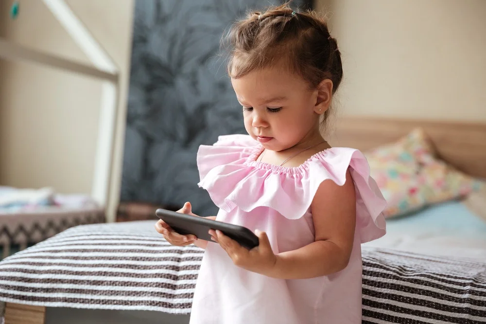 storyblocks-image-of-serious-little-girl-child-indoors-using-mobile-phone-looking-aside_rClxujipcZ.jpg