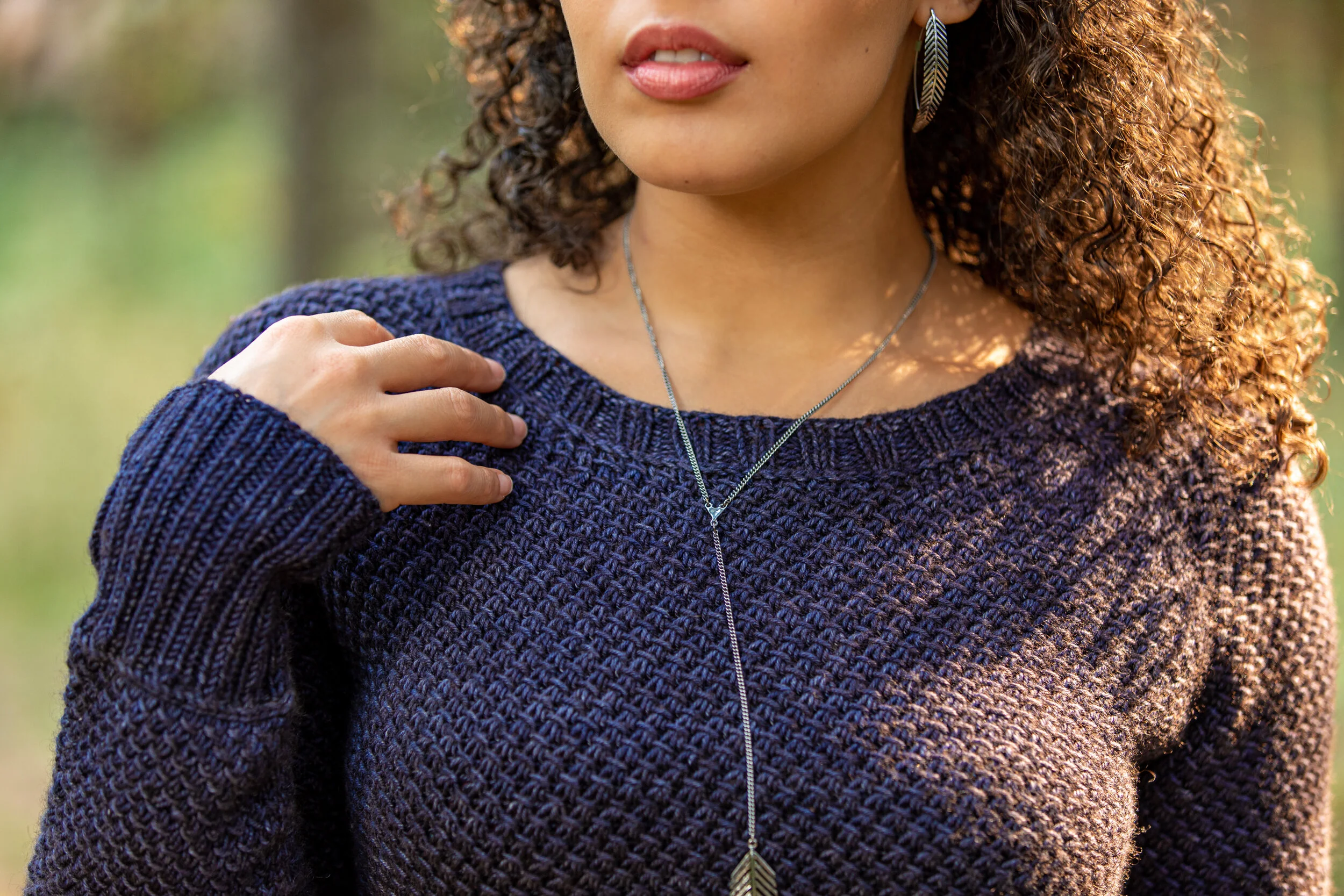 Closeup of the wide, round neck and lateral braid detail of the top-down Nydia sweater designed by Vanessa Smith in the PNW. Long 2x2 ribbed cuffs are also set off by the fun-to-knit horizontal braids