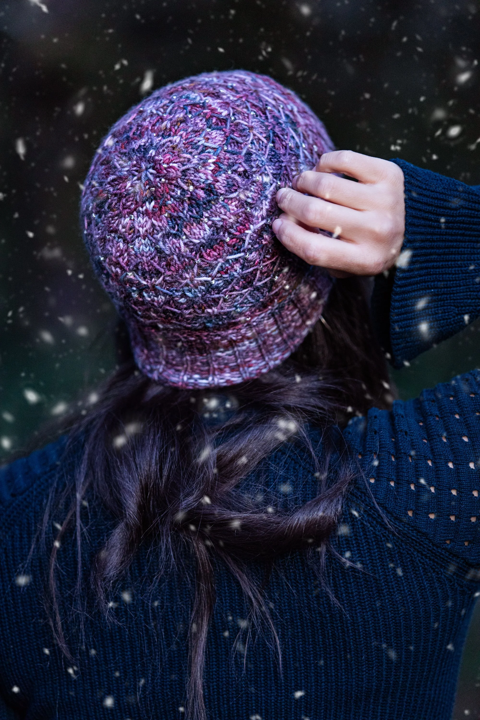A closeup view of the crown in a beautiful handknit hat pattern inspired by Lorelai and Rory Gilmore. Beads knit into the fabric resemble winter lights and snowflakes in this pattern by Vanessa Smith.