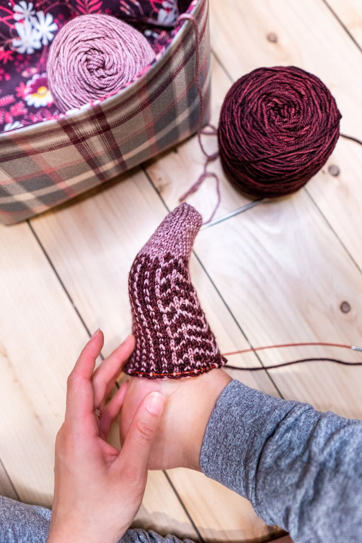 Side profile view of a toe-up Kestra Sock on the needles, showing its cozy fit and the geometric colorwork stitch details. Socks knit up quickly in a DK weight yarn and this pattern by Vanessa Smith.