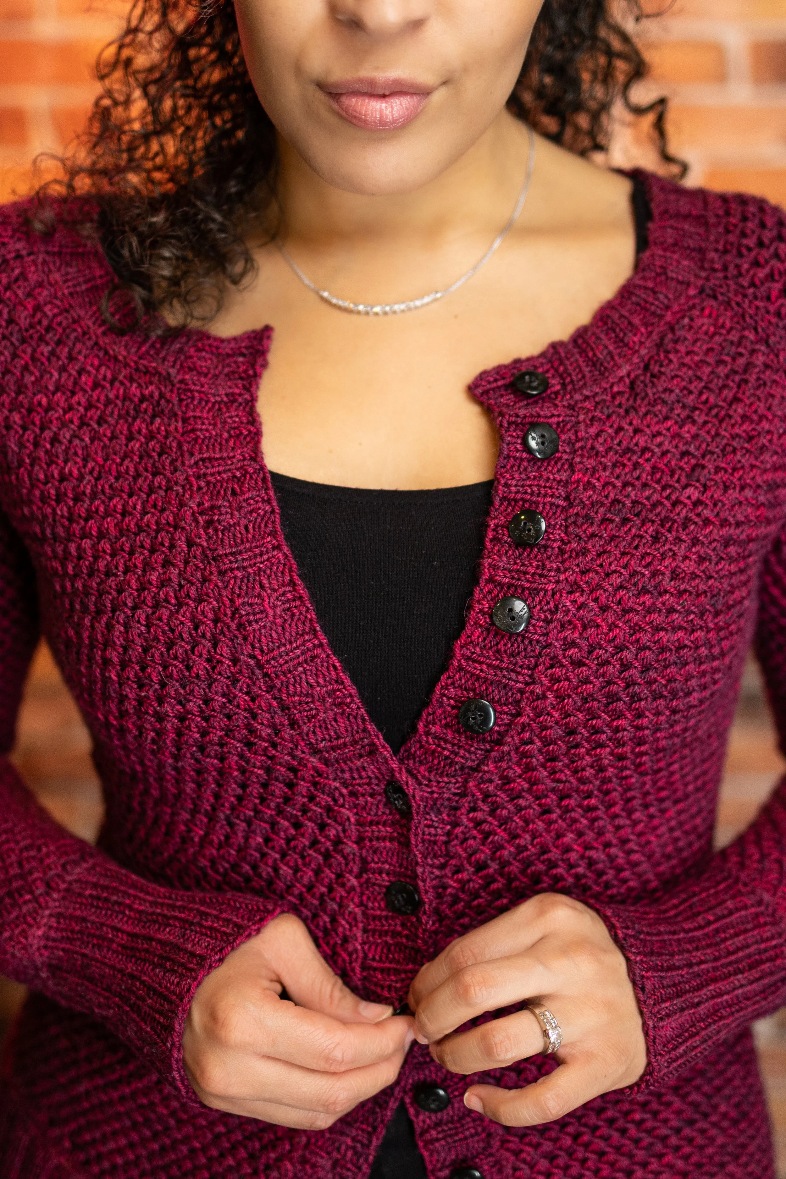 Close-up of the classic button band and flattering scoop neckline on the Nydia Cardigan, a modular top-down knit designed by BIPOC modern knitting designer Vanessa Smith for petite and plus size women
