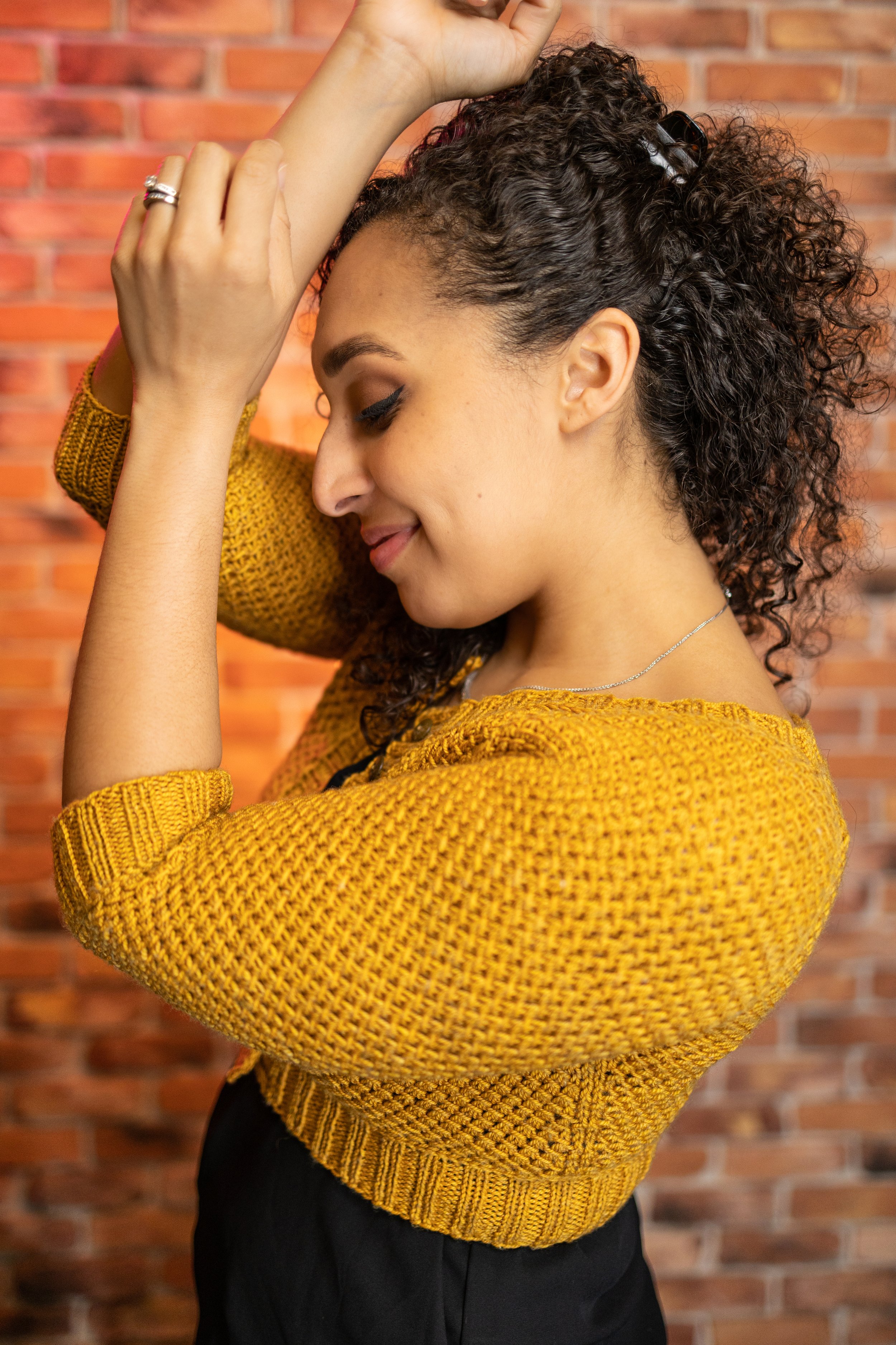 Pacific Northwest knitting designer Vanessa Smith wears her fun and quick-to-knit little yellow sweater, a cropped Nydia Cardigan with three-quarter length raglan sleeves and an addictive lace texture
